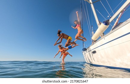 Multiracial friends jumping out of boat in the sea while having fun in their summer vacation 