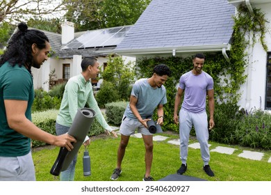 multiracial friends preparing for outdoor yoga session, smiling and holding mats in garden. fitness, wellness, friendship, exercise - Powered by Shutterstock