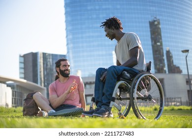 Multiracial friends relaxing in the park - Portrait of two adult in the city ; african american man with weelchair having conversation with his hispanic friend with an prosthetic leg - Powered by Shutterstock