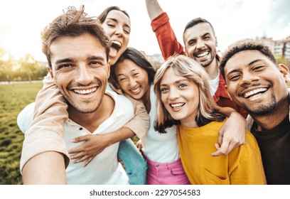 Multiracial friends taking selfie picture with smart mobile phone outside - Group of young people smiling at camera outdoors - Friendship concept with guys and girls enjoying summer vacation  - Powered by Shutterstock