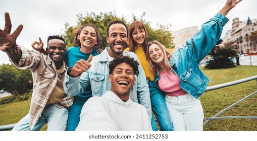 Multiracial friends taking selfie with smart mobile phone outside - Happy young people smiling at camera on city street - Youth community concept with guys and girls hanging out on summer day  - Powered by Shutterstock