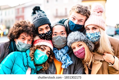 Multiracial friends taking selfie wearing face mask and winter clothes - New normal lifestyle concept with young people having fun together outside - Bright filter with focus on central asian guy