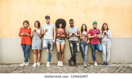 Multiracial friends using smartphone against wall at university college backyard - Young people addicted by mobile smart phone - Technology concept with always connected milenials - Filter image