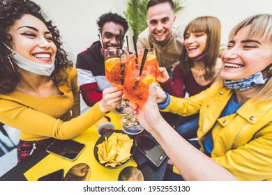 Multiracial Friends Wearing Face Masks Drinking Cocktails At Bar Restaurant - New Normal Friendship Concept With Young People Enjoying Meal In Backyard Party - Focus On Glasses