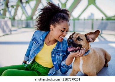 Multiracial Girl Sitting And Resting With Her Dog Outside In The Bridge, Training Him, Spending Leisure Time Together. Concept Of Relationship Between Dog And Teenager, Everyday Life With Pet.