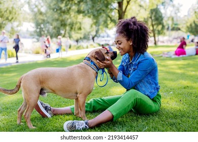 Multiracial girl sitting and resting with her dog outside in the park, training him, spending leisure time together. Concept of relationship between dog and teenager, everyday life with pet. - Powered by Shutterstock