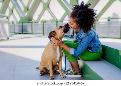 Multiracial Girl Sitting And Resting With Her Dog Outside In The Bridge, Training Him, Spending Leisure Time Together. Concept Of Relationship Between Dog And Teenager, Everyday Life With Pet.