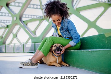 Multiracial Girl Sitting And Resting With Her Dog Outside In The Bridge, Training Him, Spending Leisure Time Together. Concept Of Relationship Between Dog And Teenager, Everyday Life With Pet.