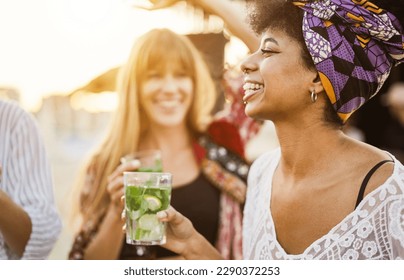 Multiracial girls having fun dancing and drinking with cocktails at bar on the beach - Focus on african girl ear - Powered by Shutterstock