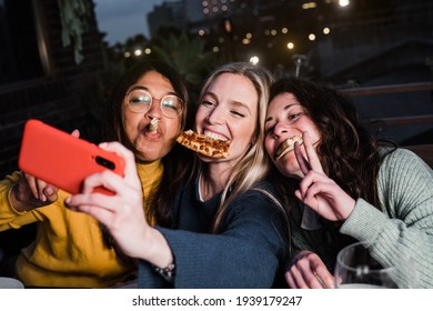 Multiracial girls having fun together outdoors in restaurant while taking selfie with smartphone - Main focus on center girl face - Powered by Shutterstock