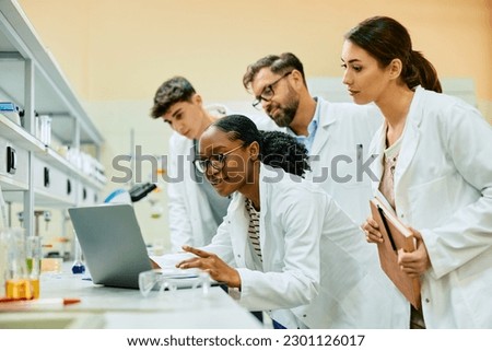Multiracial group of biochemists using laptop while analyzing scientistic data in a laboratory. ストックフォト © 