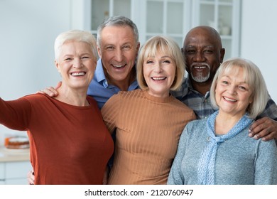 Multiracial group of cheerful positive senior people men and women in casual outfits taking selfie together while having home party, hugging and smiling at camera, kitchen interior - Powered by Shutterstock