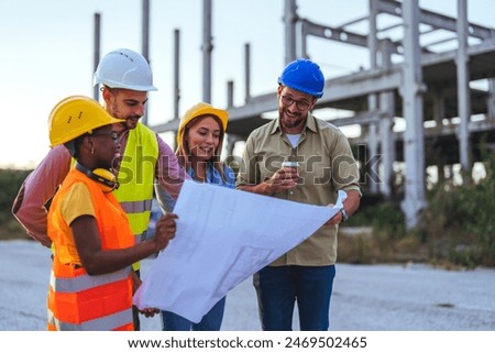 A multiracial group of construction professionals in hard hats and safety vests actively discuss a blueprint at a building site.