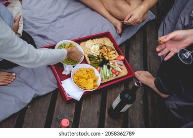 Multiracial Group Drinking Wine And Eating A Tray With Guacamole (avocado And Tomato), Nachos And A Table With Pickles, Celery, Strawberries, Olives, Cheese, Hearts Of Palm, Cookies, Nuts And Ham