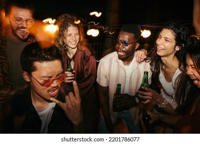 A Multiracial Group Of Friends Is Drinking Beer And Having A Good Time At The Rooftop Night Party. Open-air Clubbing Concept.