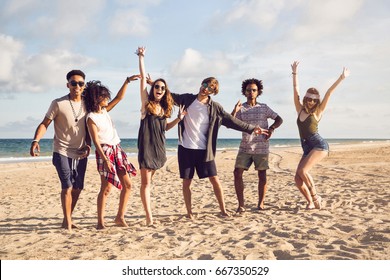 Multiracial group of friends enjoying a day at beach and jumping - Powered by Shutterstock