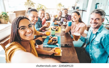 Multiracial group of friends having dinner party sitting at coffee bar table - Young people enjoying meal on morning brunch time - Life style concept with women and men at lunch break cafe bar - Powered by Shutterstock