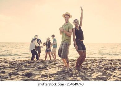 Multiracial Group Of Friends Having A Party At Beach. There Are Asiatic, Black And Caucasian Persons. Friendship, Immigration, Integration Concepts. Also Refers To Summer And Party.