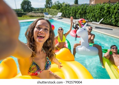 Multiracial group of friends having party in a private villa with swimming pool - Happy young people chilling with shaped air mattresses - Powered by Shutterstock