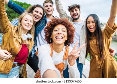 Multiracial group of friends taking selfie pic outside - Happy different young people having fun walking in city center - Youth lifestyle concept with guys and girls enjoying day out together  - Powered by Shutterstock