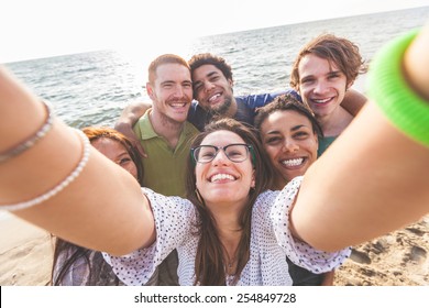 Multiracial Group Of Friends Taking Selfie At Beach. One Girl Is Asiatic, Two Persons Are Black And Three Are Caucasian. Friendship, Immigration, Integration And Summer Concepts.