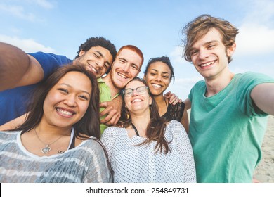 Multiracial group of friends taking selfie at beach. One girl is asiatic, two persons are black and three are caucasian. Friendship, immigration, integration and summer concepts. - Shutterstock ID 254849731