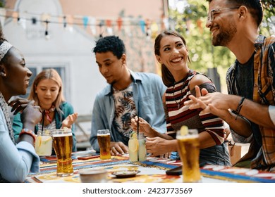 Multiracial group of friends talking while gathering in a cafe. Focus is on woman drinking cocktail.