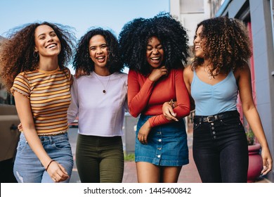 Multiracial Group Of Friends Walking Down The City Street. Four Young Women Walking Outdoors On Road Having Fun.