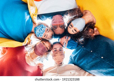 Multiracial Group Of Friends Wearing Protective Face Masks Taking A Selfie - New Normal Friendship Concept With Young People Looking Down At Camera And Laughing - Bright Filter