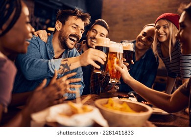 Multiracial group of happy friends having fun while toasting with beer in a bar. - Shutterstock ID 2281411833