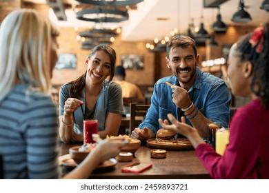 Multiracial group of happy friends talking while eating in a pub. - Powered by Shutterstock