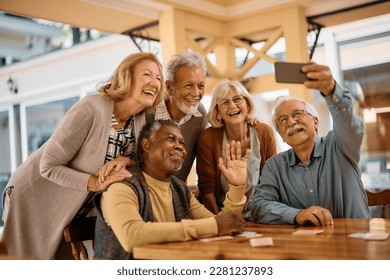 Multiracial group of happy senior friends taking selfie with smart phone in nursing home.  - Powered by Shutterstock