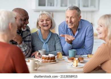 Multiracial group of happy senior people sitting around table drinking tea with cake and having conversation, smiling and laughing, having home party or enjoying time at nursing home - Shutterstock ID 2113058915