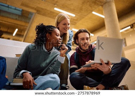 Multiracial group of happy students using laptop at the university.