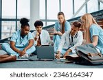 Multiracial group of medical students using computer while studying in lecture hall. 