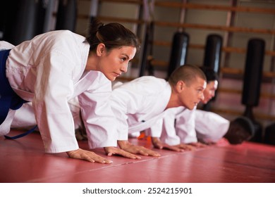 Multiracial group of men and women warming up before karate training and doing push-ups in gym. - Powered by Shutterstock