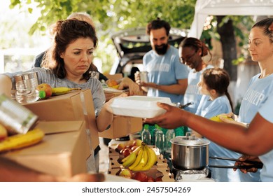 Multiracial group offers assistance by distributing food to the poor and needy. Volunteers of different ethnicities join together to aid homeless people by participating in humanitarian food drive.