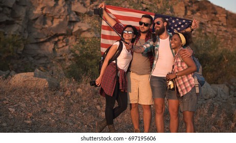 Multiracial group of people embracing and posing with American flag on coast while traveling. - Powered by Shutterstock