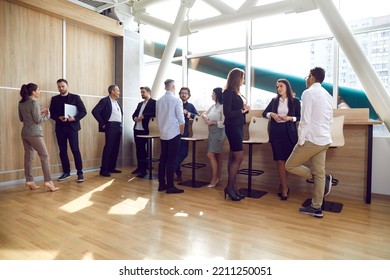 Multiracial group of people gather in a modern office with laminate flooring after a business event or a corporate team meeting, discuss latest news and talk about work stuff - Shutterstock ID 2211250051