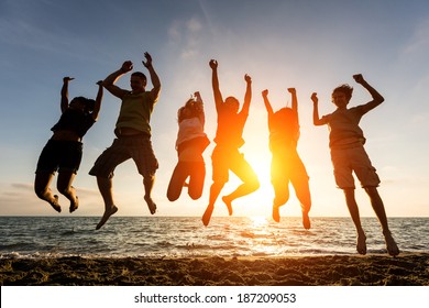 Multiracial Group Of People Jumping At Beach, Backlight