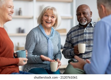 Multiracial group of positive senior men and women sitting in circle, drinking tea and having conversation, smiling and laughing, having home party or enjoying time at nursing home, closeup - Powered by Shutterstock