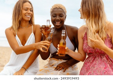 multiracial group of three female friends having fun drinking beers during a summer beach party. Friendship and summer travel - Powered by Shutterstock