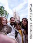 Multiracial group of tourists taking a happy selfie with sagrada familia in the background during weekend trip. Vertical image with copy space.