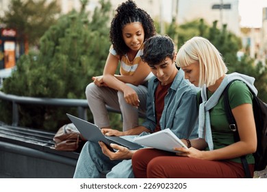 Multiracial group of university students e-learning on laptop at campus. Focus is on male student.