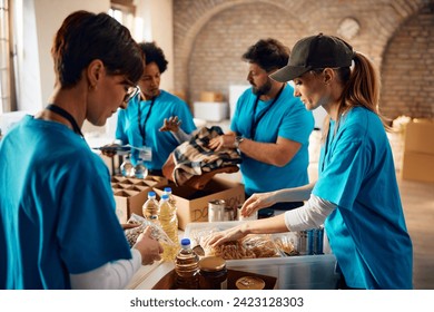 Multiracial group of volunteers packing groceries at community food bank.  - Powered by Shutterstock