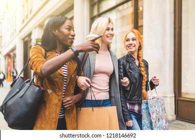 Multiracial Group Of Women Shopping And Walking In London. Three Girls, Mixed Race Group, Having Fun In The City While Shopping. Best Friends Sharing Happy Moments Together