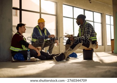 Multiracial group of worker talking while having lunch break at construction site.