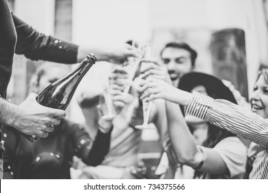 Multiracial group of young friends having fun drinking and toasting glasses of champagne on university stairs - Happy people celebrating graduation with a bottle of prosecco in city outdoor  - Powered by Shutterstock