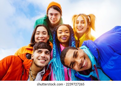 Multiracial group of young happy friends meeting outdoors in winter, wearing winter jackets and having fun - Multiethnic millennials bonding in a urban area, concepts about youth and lifestyle