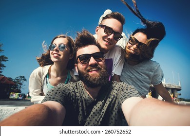 Multiracial group of young hipster friends make selfie photo with smartphone camera in Phuket while traveling across Thailand on vacation. Funny outdoor activity of young students away from home.